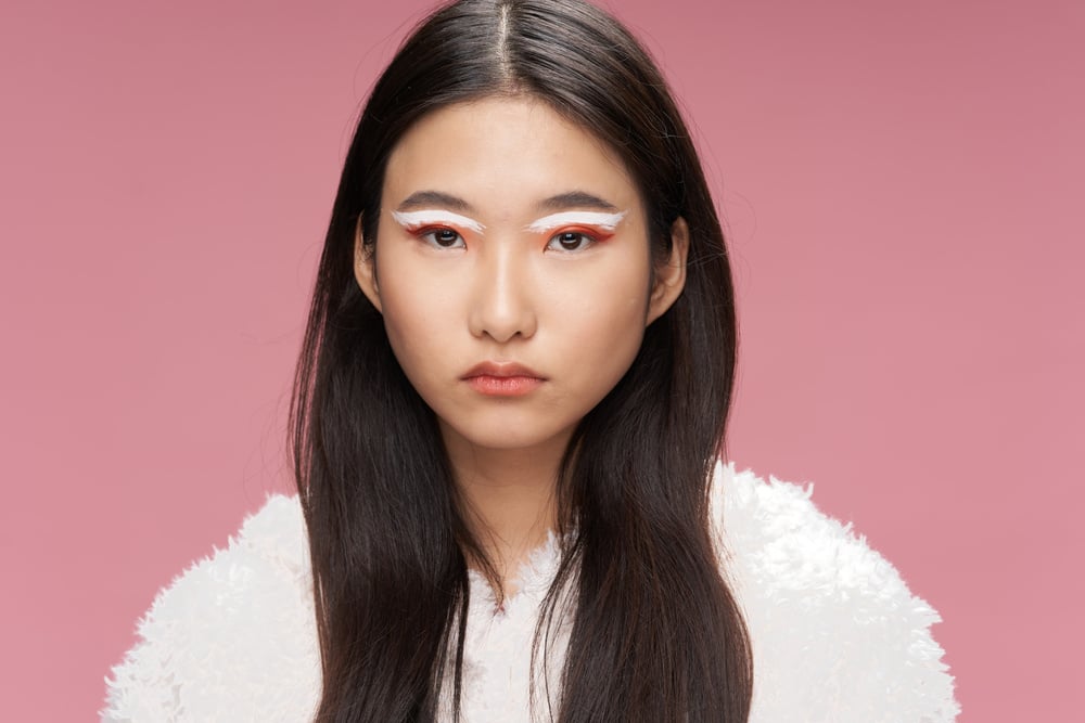 Serious Woman with White Eyeshadow on Pink Background